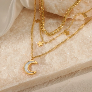 Three-layer gold stainless steel necklace with star and moon pendants on a stone surface