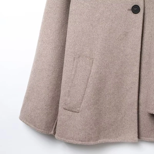 Detail of wool coat hem with visible pocket stitching and black button texture