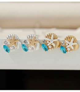 Detailed close-up of ocean-themed earrings with starfish, shells, pearls and blue crystals