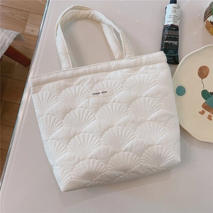 Detailed view of the shell quilting pattern and simple wish patch on a white tote bag