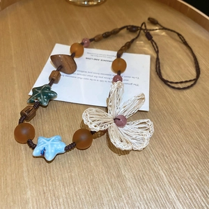 Detail of star pattern leather cord necklace with ceramic starfish and woven flower charm