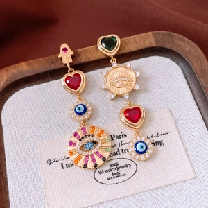 Detail of vintage gold earrings with zircon evil eye and hamsa hand charms on display