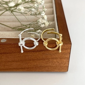 Detailed view of silver and gold geometric T-bar rings displayed on a wooden jewelry tray