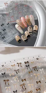 Macro detail of 3D bow nail art stickers with gold foil and pink gradient accents
