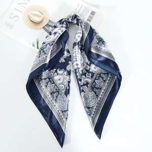 Detail of navy blue square scarf featuring intricate paisley print and silky texture