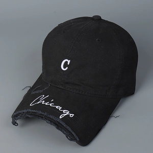 Detail of black baseball cap with white C embroidery and distressed brim edge