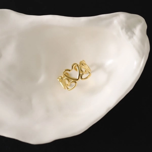 Gros plan d'une bague coeur dorée placée dans une coupelle en forme d'huître