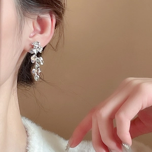 Close-up of elegant silver flower tassel earrings worn on a model in a warm setting