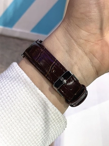 Close-up of brown leather watch strap with crocodile texture and silver H-logo buckle