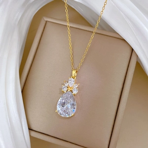 Détail d'un collier en acier titane doré avec un grand pendentif en cristal poire