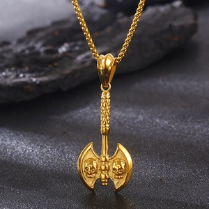 Macro shot of gold punk axe pendant with skull engraving on a vintage box chain