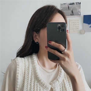 Close-up of elegant black heart earrings and pearl necklace on a model in Korean style