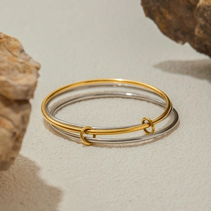 Polished gold and silver stainless steel bangles set on a natural stone background