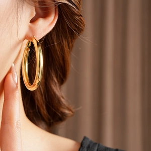 Close-up of a large polished gold hoop earring worn by a model to show stylish minimalist design