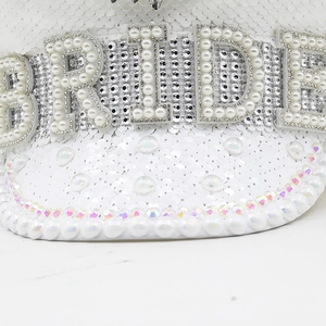 Close-up of white sequin captain hat with BRIDE pearl lettering and rhinestone trim