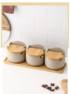 Detail of ceramic spice jars with bamboo lids and spoons on a matching wooden tray