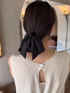 Elegant large black satin bow hair clip styled on a low bun hairstyle for women