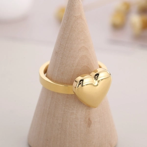 Detail of 18K gold plated heart ring on a wooden cone stand with soft focus background