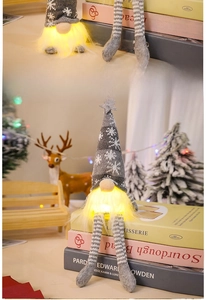 Close-up of a glowing Christmas gnome with gray knitted hat and long striped legs