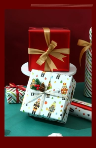 Close-up of Nutcracker and red glossy Christmas gift wrapping paper with ribbons