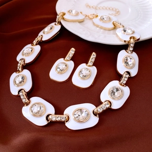 Détail d'un ensemble collier et boucles d'oreilles vintage dorés avec émail blanc