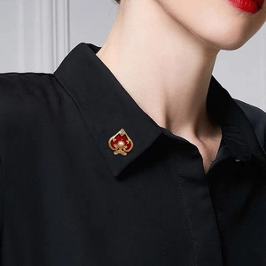 Golden ace of spades brooch with red enamel and pearl accent on a lapel