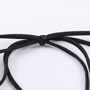 Detail shot of the black satin dress featuring intricate knot tie shoulder straps