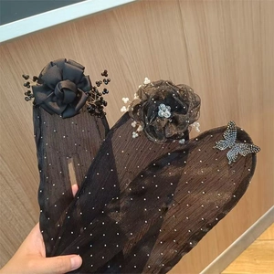 Detail of sheer black bun maker with floral, pearl, and butterfly embellishments