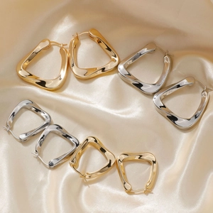 U-shaped irregular geometric metal earrings in gold and silver on champagne silk fabric