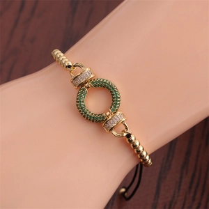 Detailed macro shot of a gold bead bracelet with green and white cubic zirconia stones