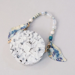 Detail of round marble acrylic handbag with silk scarf and beaded handle decoration