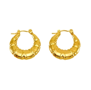 Macro detail of gold-tone croissant hoop earrings with textured ripple design