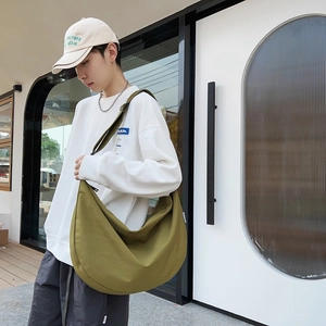 Olive green large capacity oxford crossbody bag worn by model in an outdoor urban setting
