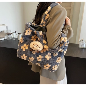 Detail of plush tote bag featuring gray and yellow floral patterns with a cute bear charm