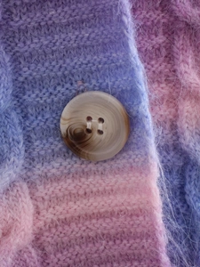 Close-up of tie-dye knit cardigan featuring plush texture and amber marble button