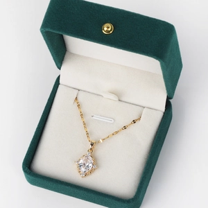 Close-up of golden diamond cross necklace inside an elegant green velvet jewelry box