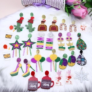 Colorful acrylic festive earrings collection with glitter on white faux fur background