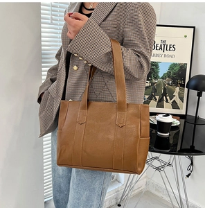 Detailed side view of a large brown PU leather tote bag in a cozy lifestyle setting