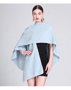 Detail showing high-quality light blue knitted poncho with elegant oversized gold earrings
