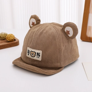 Détail du bonnet bébé en velours côtelé marron avec oreilles 3D et écusson d'ours