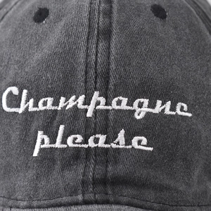 Washed dark grey cotton baseball cap featuring white Champagne Please script embroidery