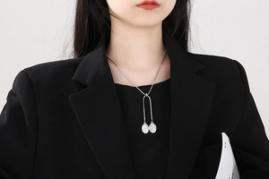 Silver snake chain necklace with double oval relief goddess charms on black blazer
