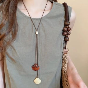 Close-up of vintage wood bead necklace with resin shell pendants worn with linen clothing