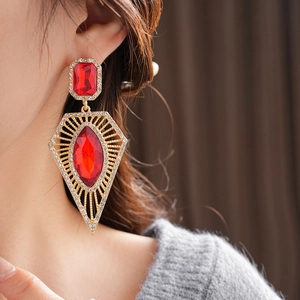 Close-up of vintage gold drop earrings with red faceted gemstones and sparkling rhinestones