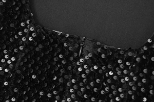 Détail macro de paillettes noires avec une fermeture éclair invisible sur une robe