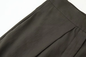 Gros plan du pantalon en sergé marron foncé avec plis élégants à la taille
