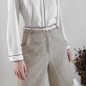 Close-up of white leather belt for women featuring a delicate floral buckle on waist