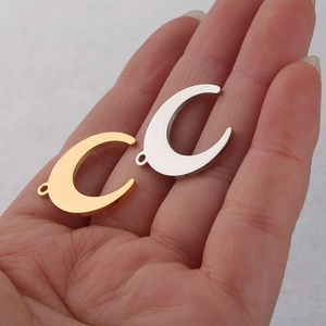Close-up of gold and silver moon pendants in palm showing scale and mirror finish