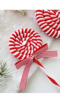 Detail of plush red and white striped lollipop ornament with a ribbon bow on pine needles