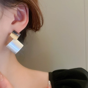 Detail view of double square brushed metal earrings on model showing size and texture